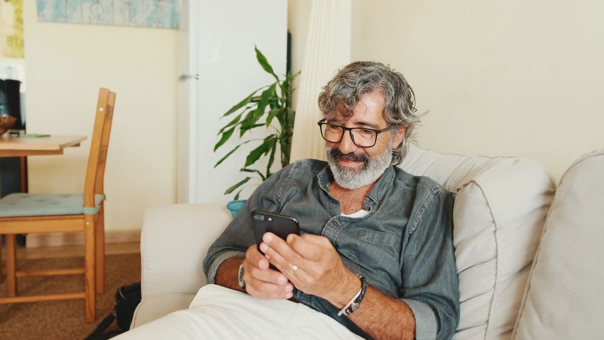 Happy client checking his phone on the couch